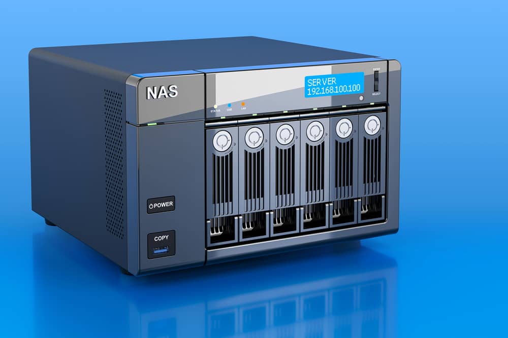 Imagen de un dispositivo NAS (Network Attached Storage) de color negro sobre fondo azul. Almacenamiento conectado a la red.